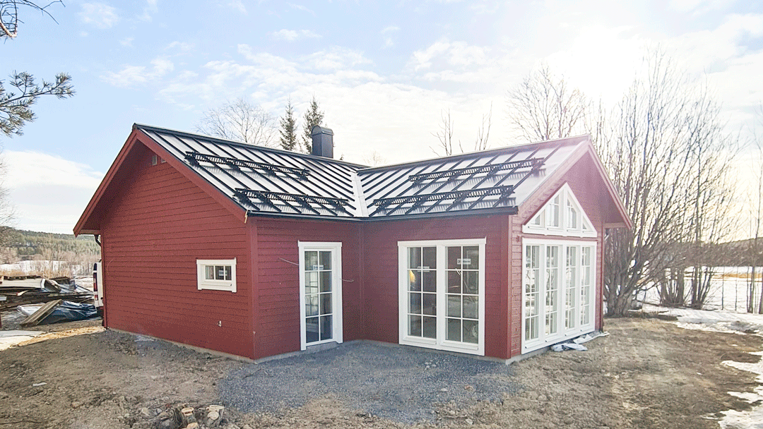 Litet rött hus vid en sjö.